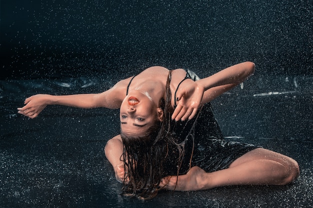 Kostenloses Foto junge schöne moderne tänzerin, die unter wassertropfen tanzt