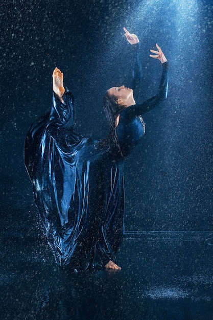 junge schöne moderne Tänzerin, die unter Wassertropfen tanzt