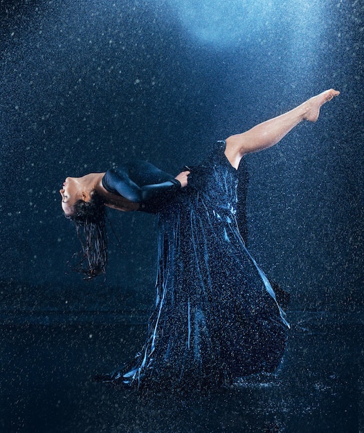 junge schöne moderne Tänzerin, die unter Wassertropfen tanzt