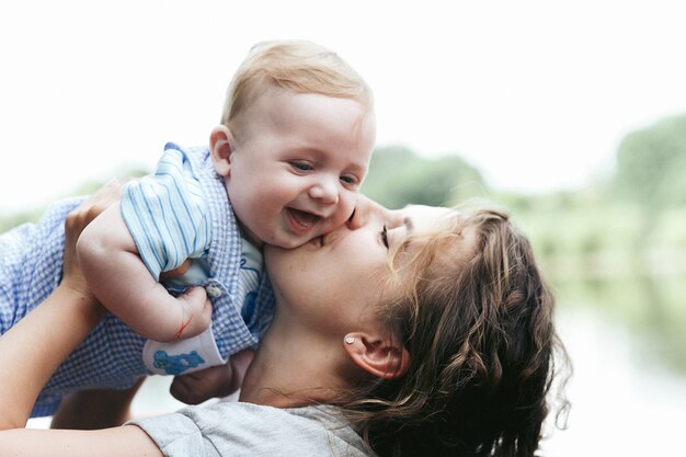 Junge schöne Mutter, die das nette kleine Babylächeln hält