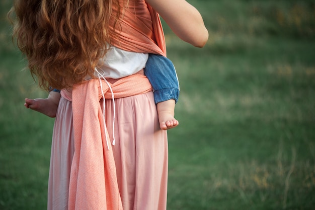 Junge schöne Mutter, die ihren kleinen Kleinkindsohn draußen umarmt