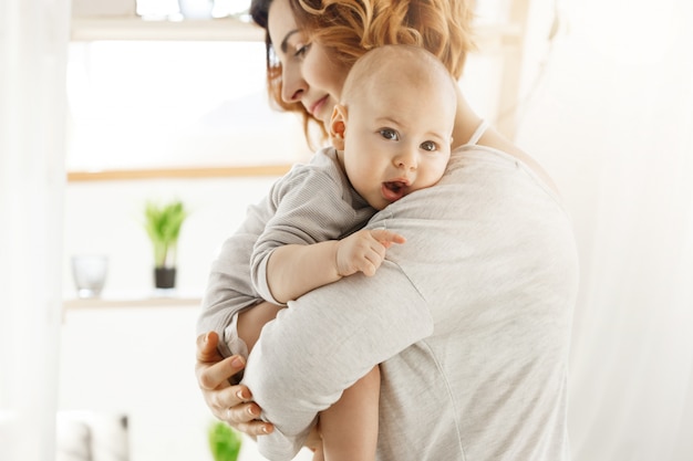 Junge schöne Mutter hält ihren kleinen neugeborenen Sohn und beruhigt ihn nach bösen Träumen. Süße Szene der Mutterschaft. Familien- und Lifestyle-Konzept.