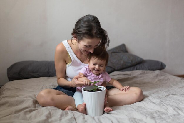 Junge schöne Mutter und Baby, um etwas über Pflanzen zu lernen Gemütlicher Hauslebensstil