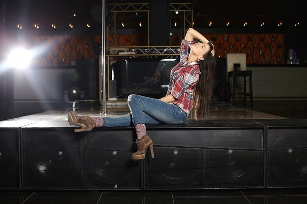 junge schöne Popstar-Sängerin mit Mikrofon sitzt vor Ort im Club