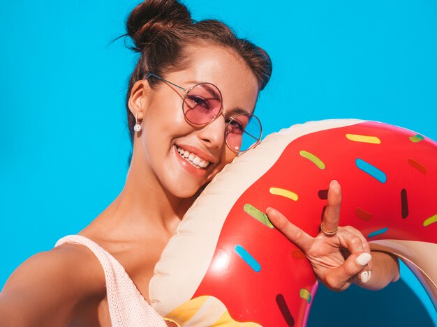 Junge schöne sexy lächelnde Hippie-Frau in der Sonnenbrille. mit Donut Lilo aufblasbare Matratze.