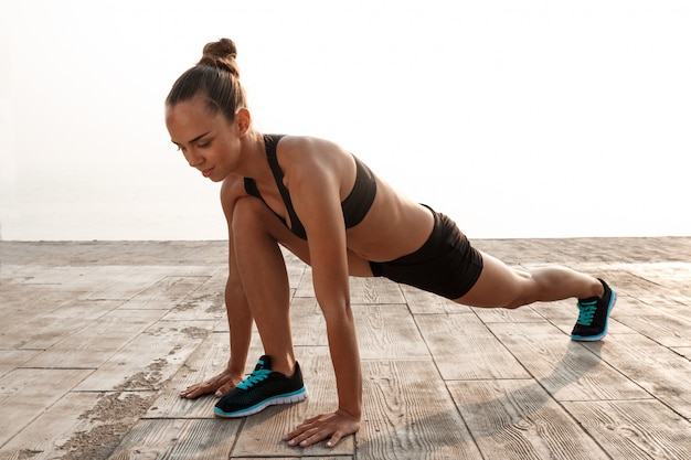 Junge schöne sportliche Mädchen, die Yoga am Meer trainieren.