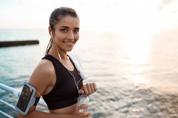 Junge schöne sportliche Mädchenausbildung bei Sonnenaufgang über dem Meer.