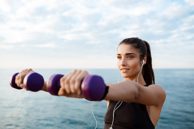 Junge schöne sportliche Mädchenausbildung bei Sonnenaufgang über dem Meer.