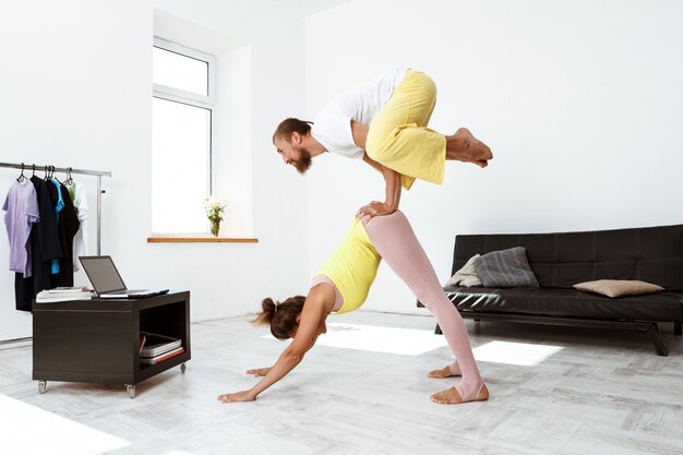 Junge schöne sportliche Paar Trainingspartner Yoga Asanas zu Hause.