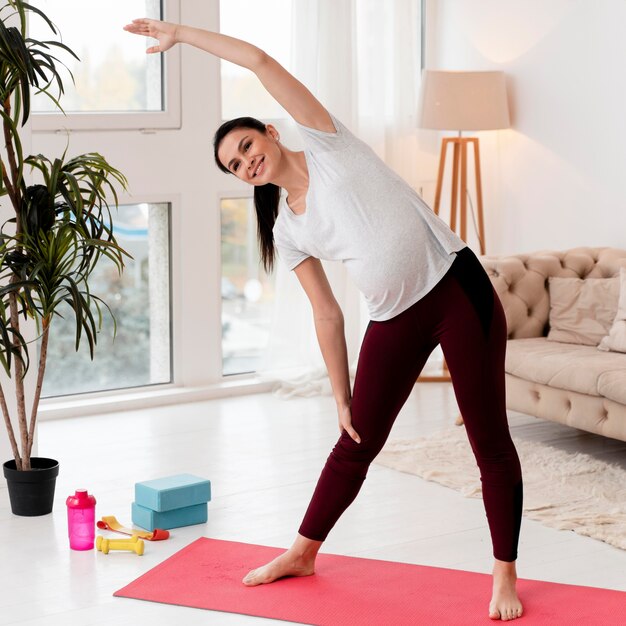 Junge schwangere Frau, die auf Fitnessmatte ausübt