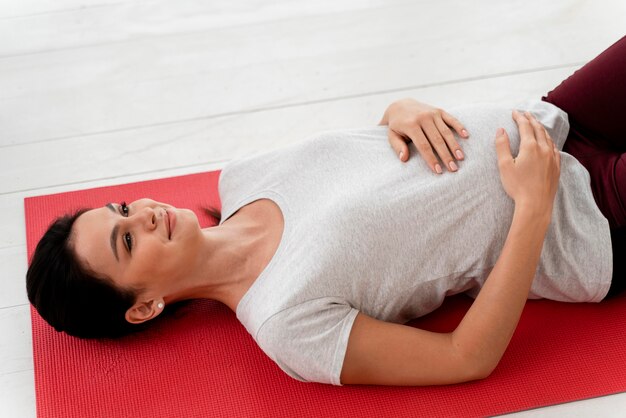 Junge schwangere Frau, die auf Fitnessmatte ausübt