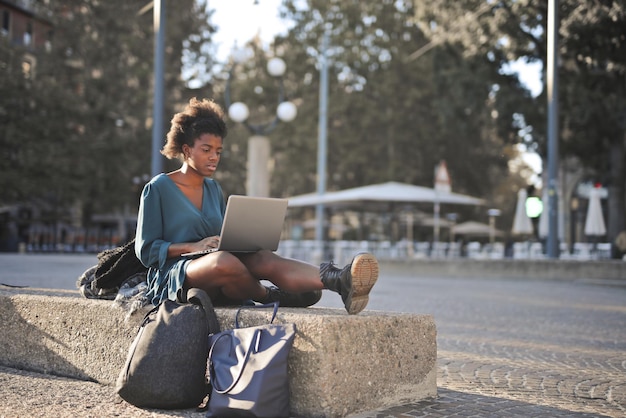 junge schwarze Frau auf der Straße mit einem Computer