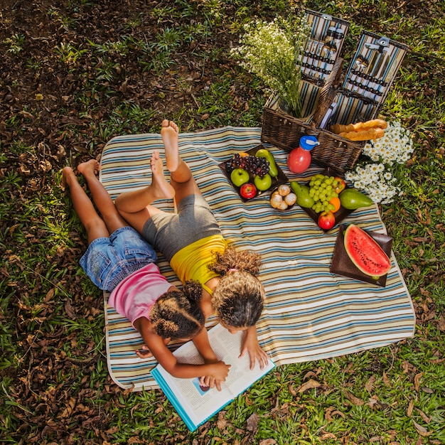 Kostenloses Foto junge schwestern lesen auf picknick tuch