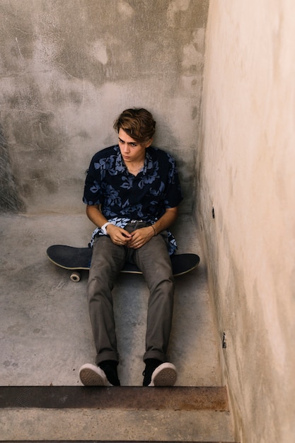 Junge sitzt auf Skateboard in konkreter Umgebung