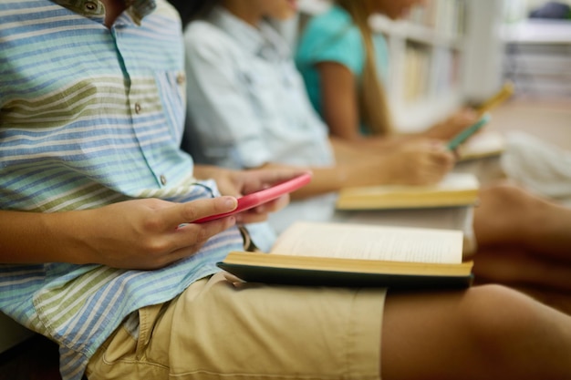 Junge sitzt mit Buch begeistert am Smartphone