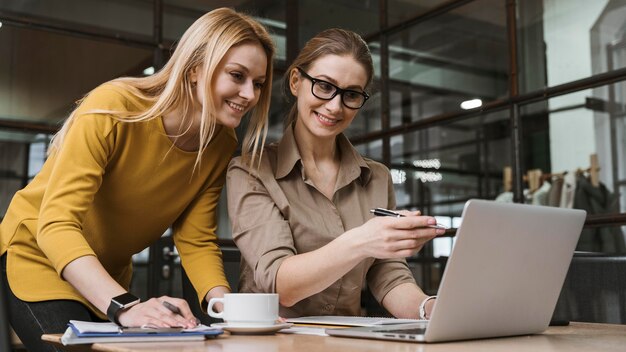 Junge Smiley-Geschäftsfrauen, die mit Laptop am Schreibtisch arbeiten