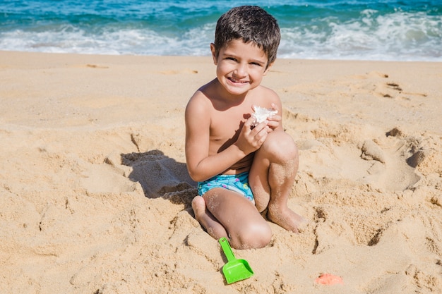 Junge spielt mit Schale am Strand