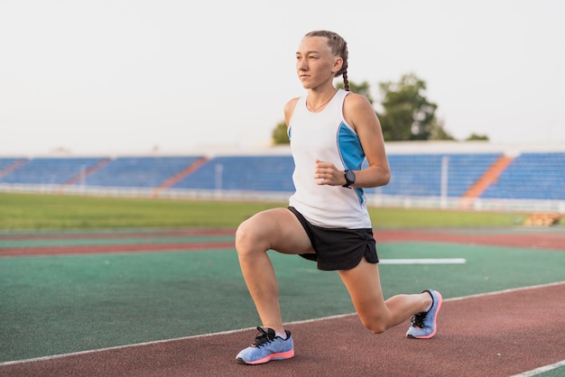 Junge sportive Frau, die am Stadion aufwärmt