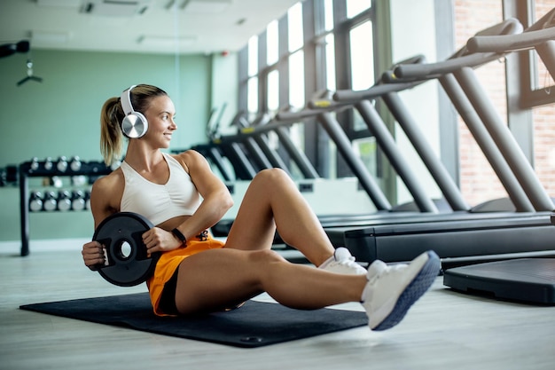 Kostenloses Foto junge sportlerin, die im fitnessstudio bauchübungen mit hantelscheiben macht