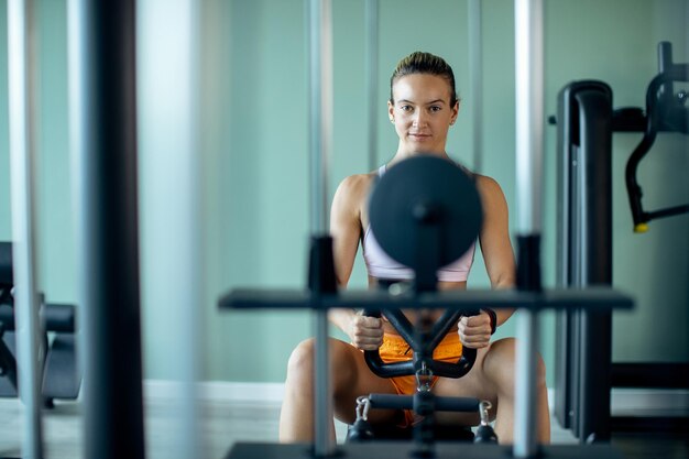 Junge Sportlerin trainiert auf Rudergerät in einem Fitnessstudio