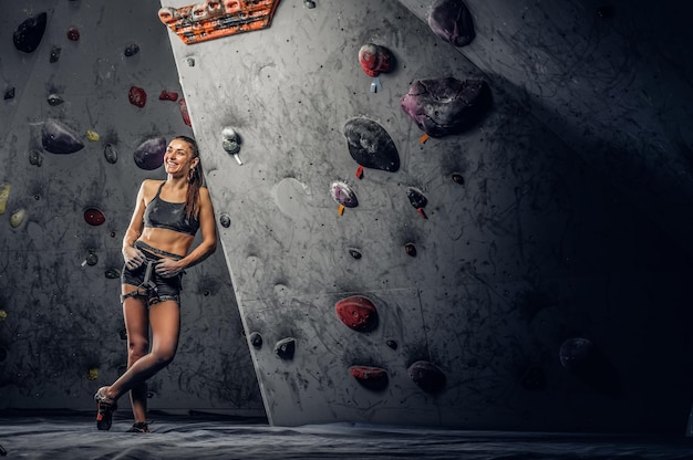 Junge sportliche Frau, die drinnen künstlichen Felsbrocken klettert.