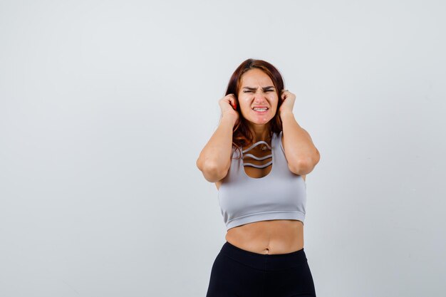 Junge sportliche Frau in einem grauen Top, das ihre Ohren bedeckt