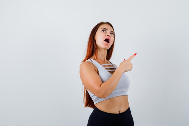 Junge sportliche Frau mit langen Haaren in einem grauen Top