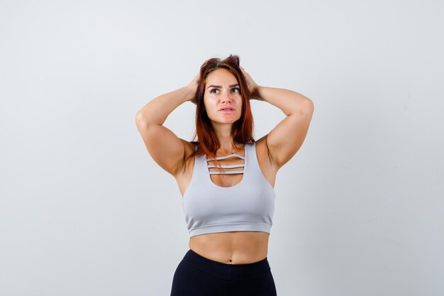 Junge sportliche Frau mit langen Haaren in einem grauen Top