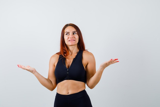 Junge sportliche Frau mit langen Haaren in einem schwarzen Top