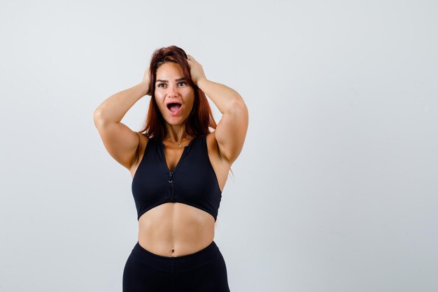 Junge sportliche Frau mit langen Haaren in einem schwarzen Top