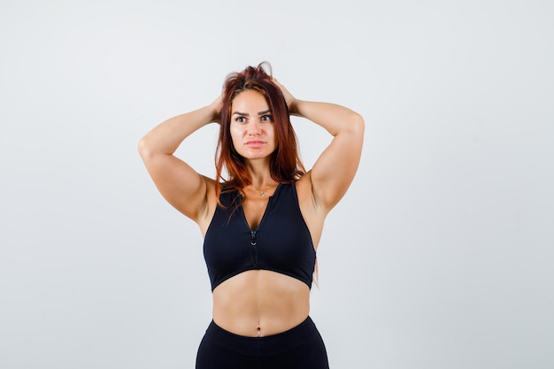 Junge sportliche Frau mit langen Haaren in einem schwarzen Top