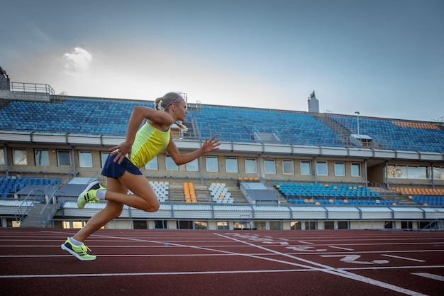 Junge Sprinterin, die während des Trainings im Leichtathletikstadion auf dem Laufbandrennen läuft.