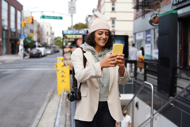 Kostenloses Foto junge stilvolle frau in der stadt, die smartphone zur erkundung nutzt