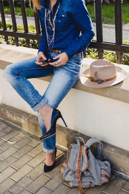 Kostenloses Foto junge stilvolle hübsche frau, die ein telefon hält, gekleidet in jeanshemd und jeans