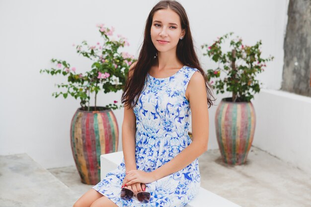 Junge stilvolle schöne Frau im blau bedruckten Kleid, Sonnenbrille, fröhliche Stimmung, Mode-Outfit, trendige Kleidung, lächelnd, Sommer, Accessoires