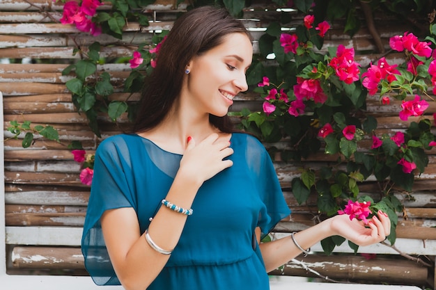 Junge stilvolle schöne Frau im blauen Kleid, Sommermodetrend, Urlaub, Garten, tropische Hotelterrasse, lächelnd