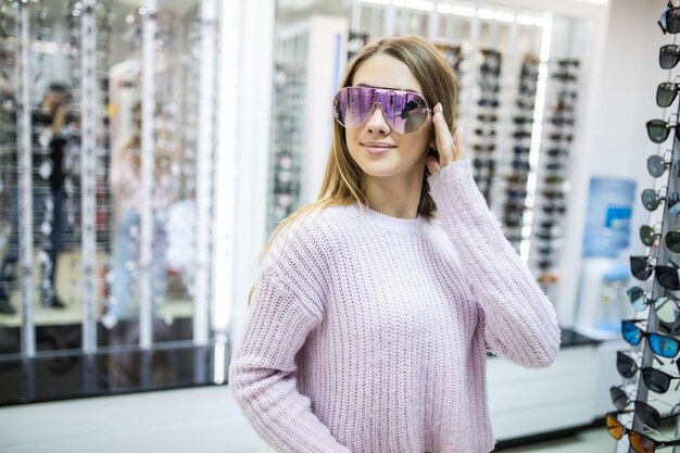 Junge Studentin bereitet sich auf das Studium vor und probiert neue Brillen für ihren perfekten Look im Laden