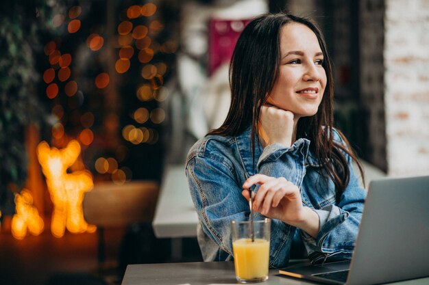 Junge Studentin, die an Laptop in der Bar arbeitet und Pizza isst