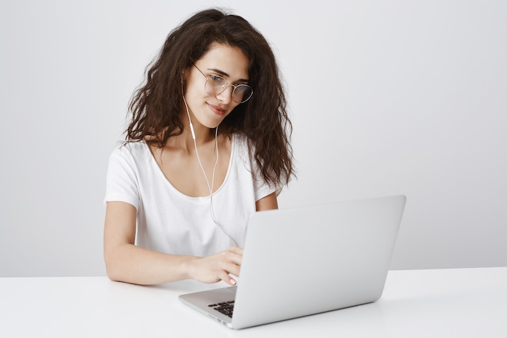 Kostenlose Foto junge studentin, die mit laptop arbeitet und an anzeige lächelt