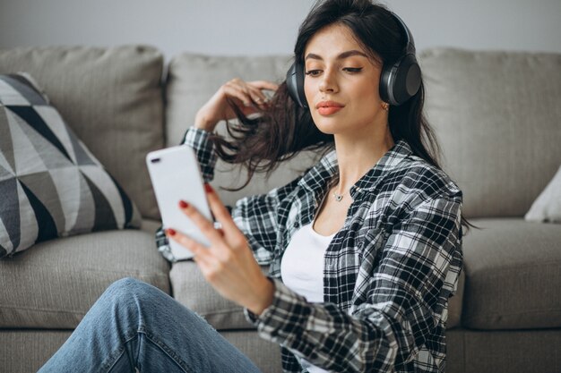 Junge Studentin, die Musik durch Telefon auf Kopfhörern hört