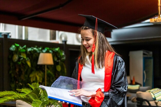 Junge Studentin mit Abschlussumhang und Blick auf ihr Notizbuch