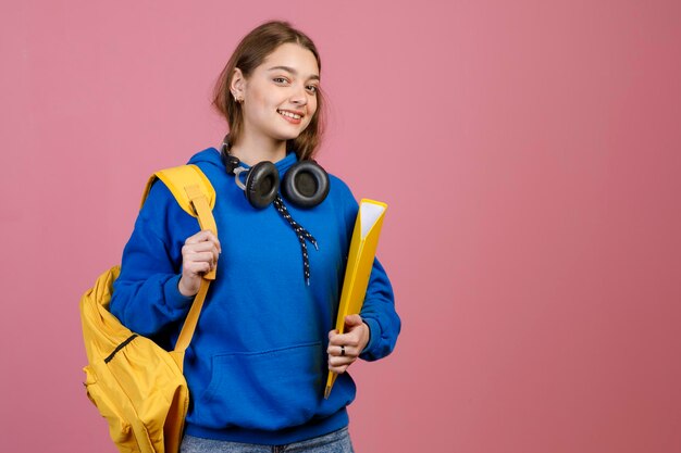 Junge Studentin mit gelbem Rucksack und Ordner lächelnd