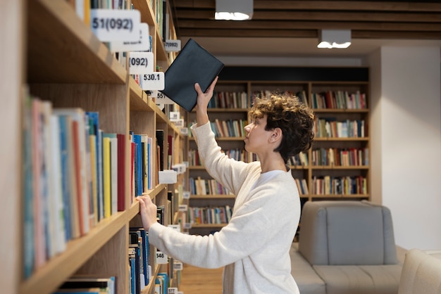 Kostenloses Foto junge studentin sucht ein buch in der bibliothek