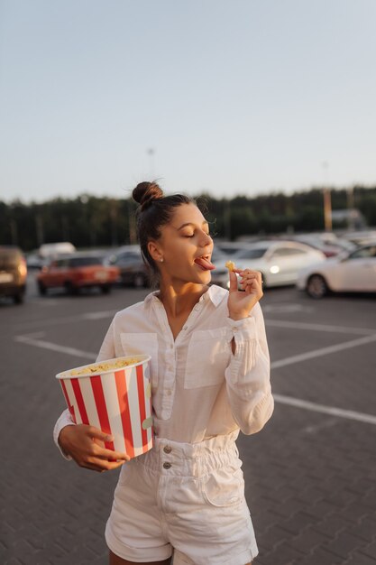 Junge süße Frau mit Popcorn auf einem Parkplatz eines Einkaufszentrums