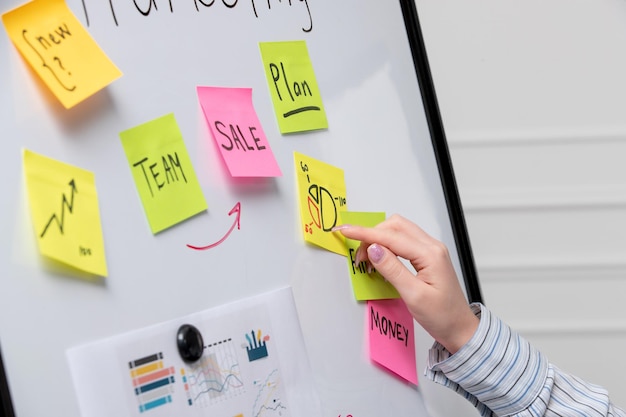 Kostenloses Foto junge süße geschäftsfrau im gestreiften hemd im büro vermarkten, die kreisdiagramm an bord erklärt