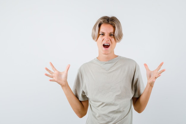 Kostenloses Foto junge teenager, die aggressiv die hände im t-shirt heben und irritiert aussehen