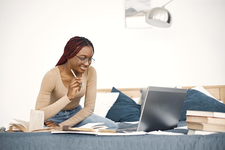 Kostenlose Foto junge teenagerin sitzt auf ihrem bett und studiert und benutzt einen laptop