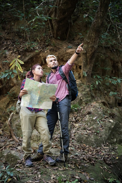 Kostenloses Foto junge touristische paar reisen auf urlaub im wald blick auf karte auf der suche nach attraktionen. reisekonzept