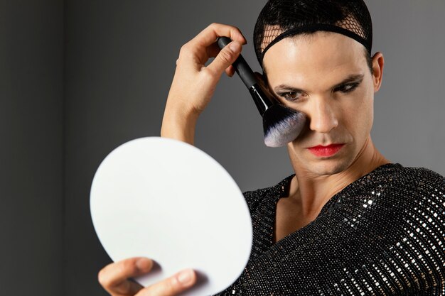 Junge Transgender-Person mit einem Make-up-Pinsel