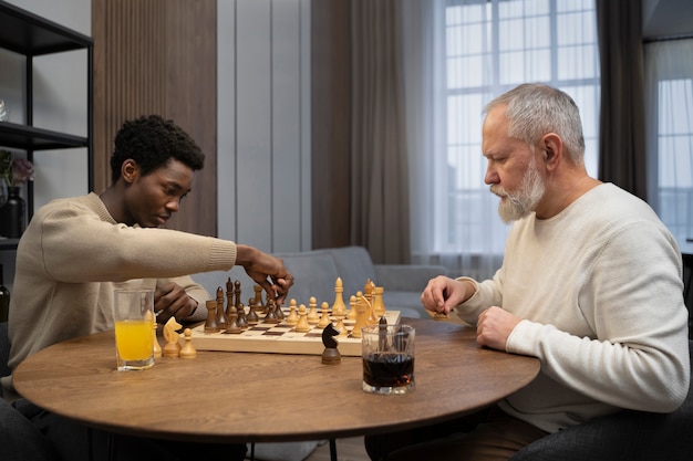 Junge und alte Männer der Seitenansicht, die Schach spielen